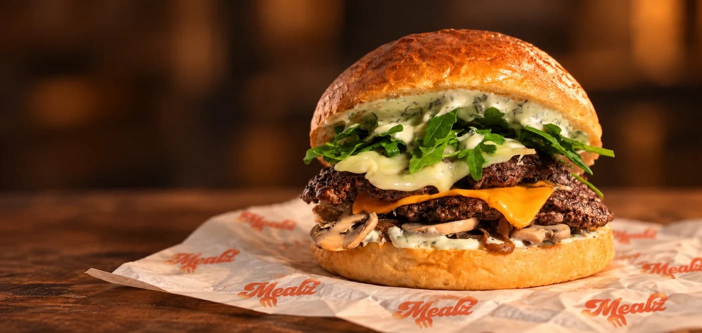 Burger MEALZ à double steak, fromages, roquette, champignons et sauce aux herbes